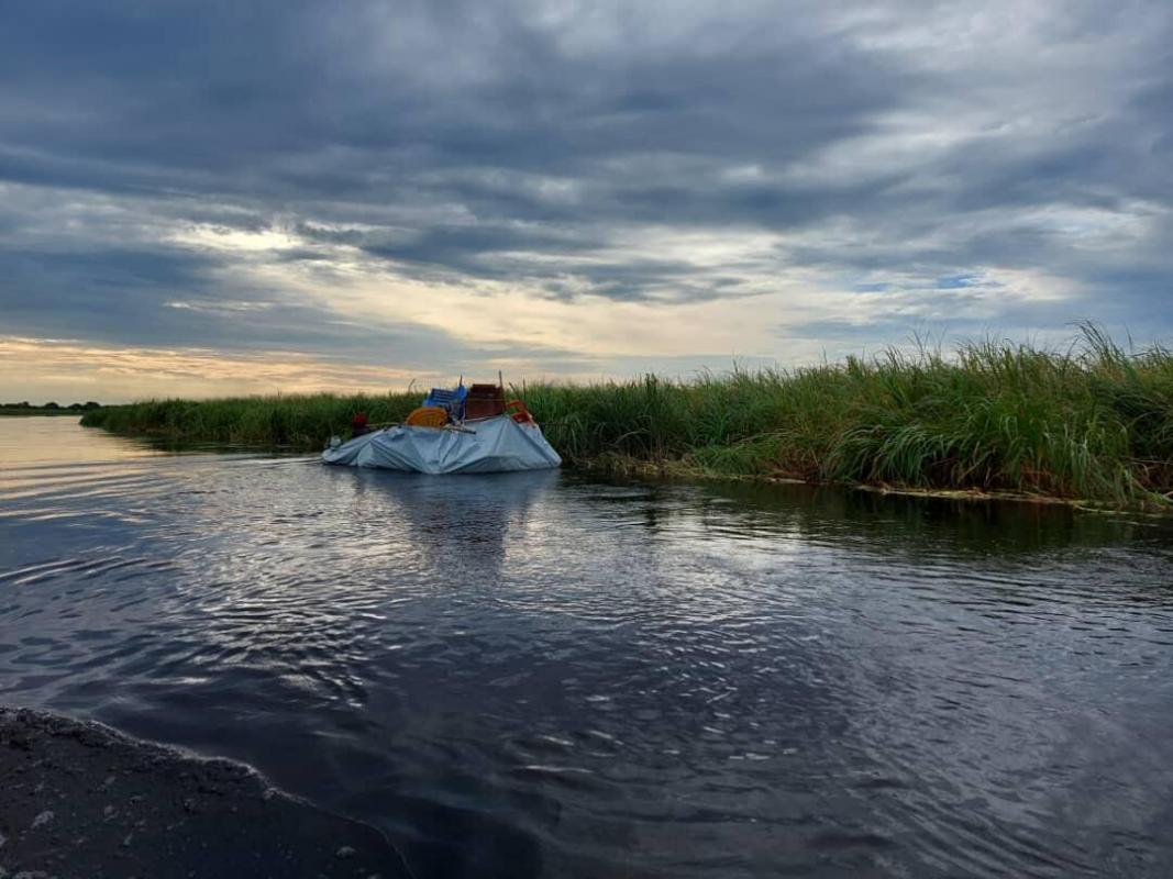 Displaced carry items through floodwaters on makeshift rafts