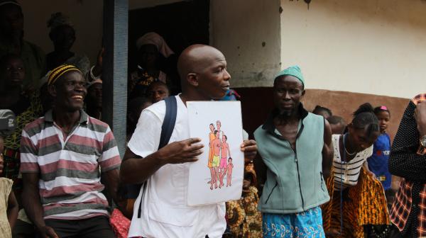 Kenema, Sierra Leone, März 2019: Im Dorf Bondayilahun klärt Gesundheitsberater Tamba Magnus Aruna mit Schautafeln über Gesundheitsprävention auf.